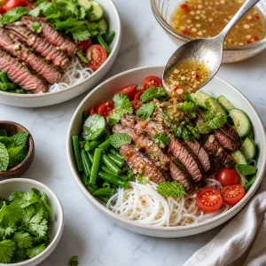 Steak noodle salad bowls being topped with dressing
