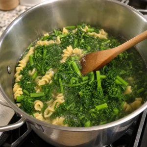 Broccoli rabe being stirred into pasta in a pot