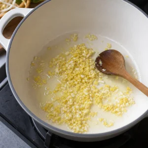 Gehackter Ingwer und Knoblauch duensten sanft in Oel