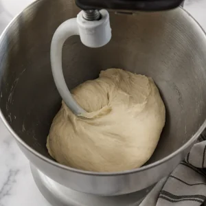 Smooth focaccia dough gathered around a dough hook
