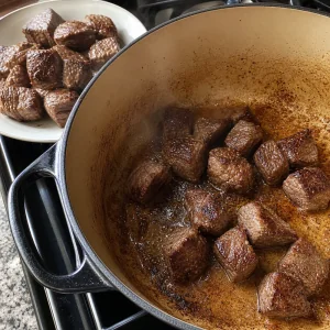 Beef cubes browning in hot oil in a Dutch oven