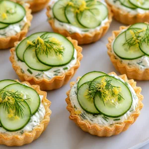 Cucumber-topped tartlets garnished with fresh dill and lemon zest.