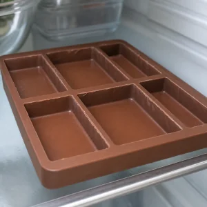 Hardened milk chocolate shells chilled in a silicone chocolate bar mold