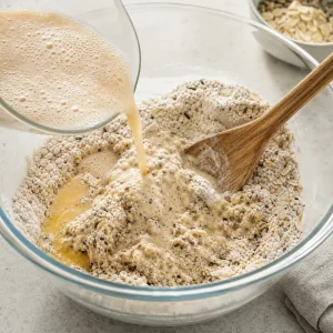 Schäumende Hefemischung und geschmolzene Butter werden zu trockenen Zutaten zu einem zottigen Teig gemischt