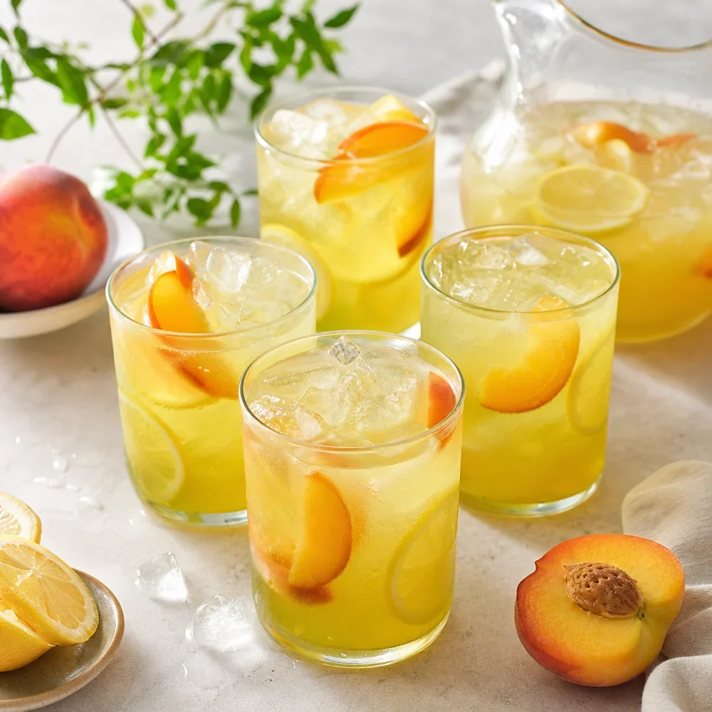 Glasses of iced peach green tea lemonade with lemon and peach slices