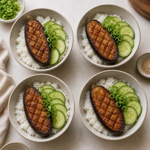 Rice bowls topped with roasted miso eggplant, cucumber, and scallions