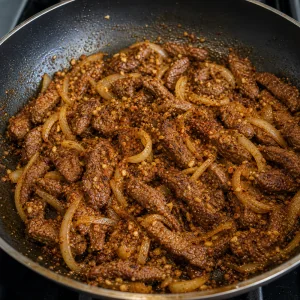 Garlic, ginger, and spices stirred into beef and onions