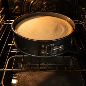 Brownie cheesecake baking in a springform pan in the oven