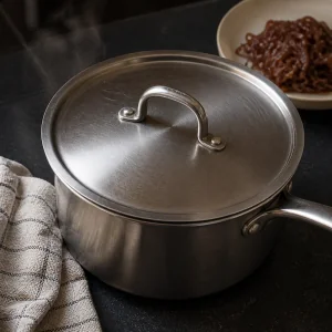 Casserole couverte qui repose hors du feu avec des oignons caramélisés à côté