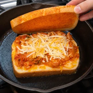 Sautiertes Kimchi wird vor dem Schließen des Sandwiches auf den Käse gelegt