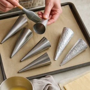 Gefettete Metallkegel liegen bereit auf einem Blech mit Backpapier