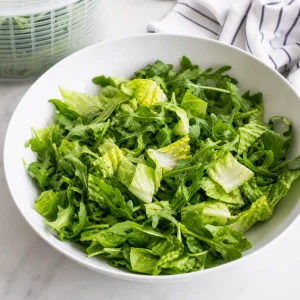Fresh washed salad greens placed in a large white serving bowl