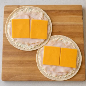 Fette di tacchino e cheddar disposte sulle tortillas con crema di formaggio alle verdure
