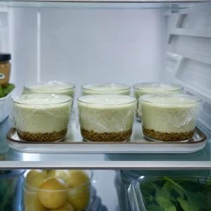 Covered pistachio cheesecake cups chilling in the refrigerator