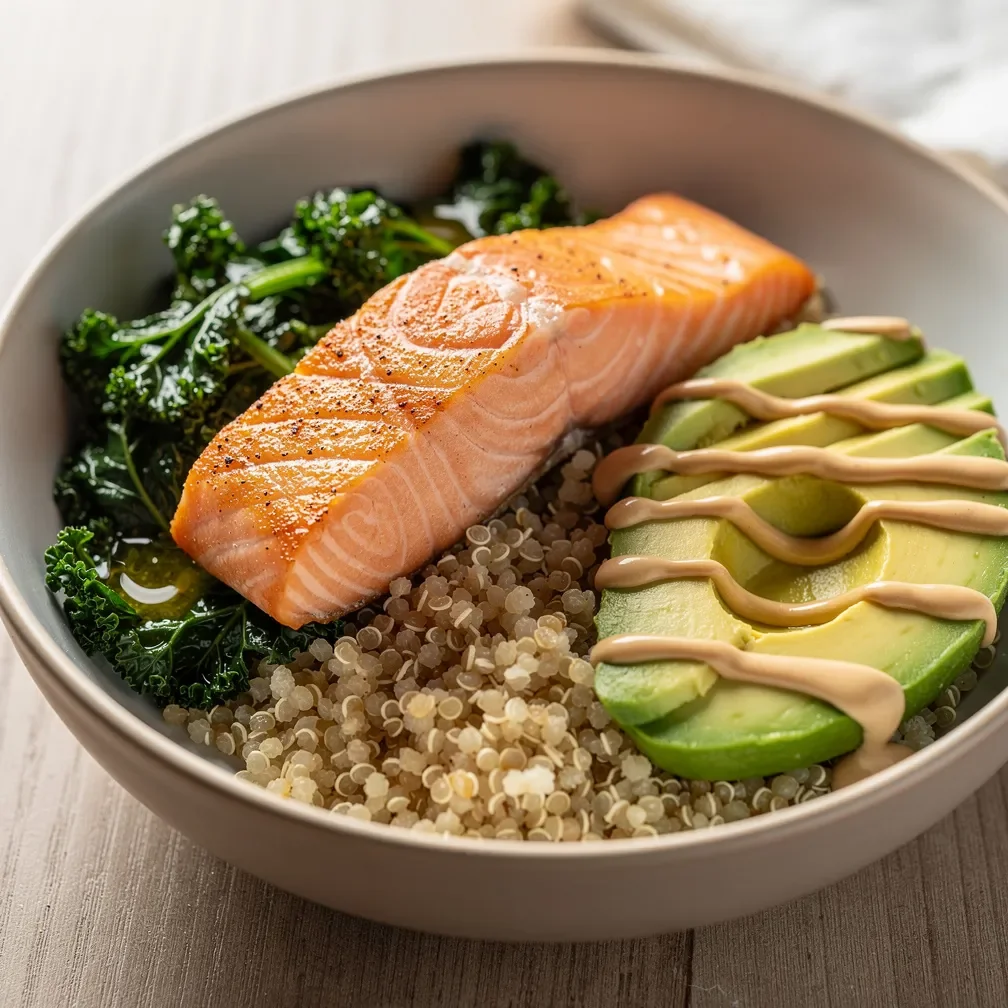 Una ciotola nutriente con salmone al secco, quinoa, cime di kale saltate e avocado a fette