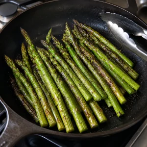 Browned asparagus in an uncovered skillet with tongs
