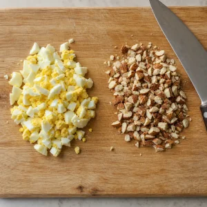 Chopped hard-boiled eggs and toasted almonds on a cutting board