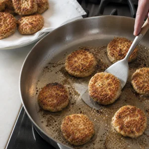 Tortitas de gefilte fish friiendose en sarten hasta dorarse y quedar crujientes