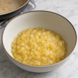 Softened buttery onions cooling in a mixing bowl