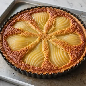 Tarte aux poires et aux amandes cuite dans le moule avec garniture dorée