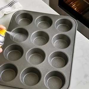 A greased 12-cup muffin pan ready for cupcake batter.