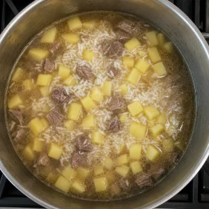 Рис и нарезанный картофель добавлены в кипящий говяжий суп