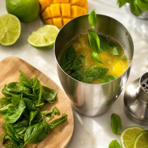 Frische Basilikumblaetter im Shaker mit Mango-Cocktail