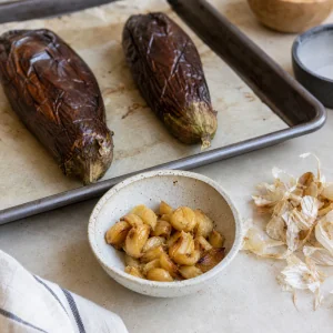 Spicchi d’aglio arrostiti pelati pronti mentre le melanzane si raffreddano