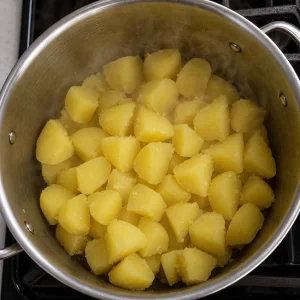 Drained potato chunks steaming in a hot pot