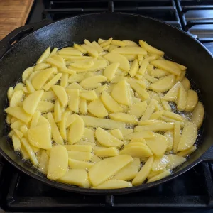 Sliced potatoes frying in hot oil in a skillet