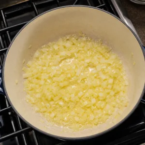 Cipolla tritata che si ammorbidisce in burro e olio d'oliva.