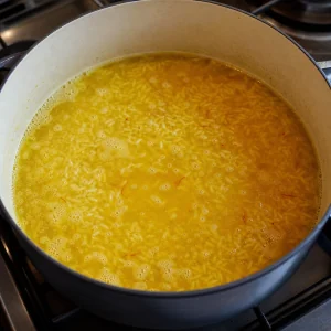 Brodo allo zafferano che sobbolle con riso tostato in pentola.