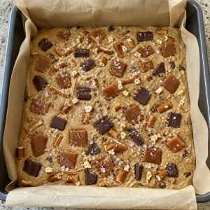 Unbaked blondie batter topped with caramel and flaky salt