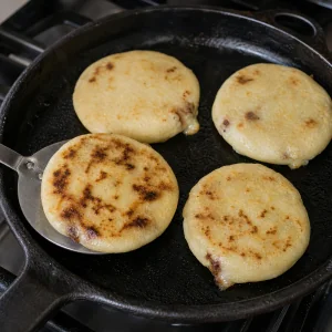 Pupusas browning on a cast-iron skillet