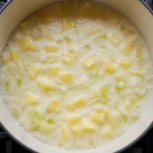 Diced potatoes simmering in a pale smoky milk soup base