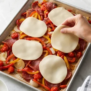 Provolone slices placed over roasted Italian sub meats and vegetables