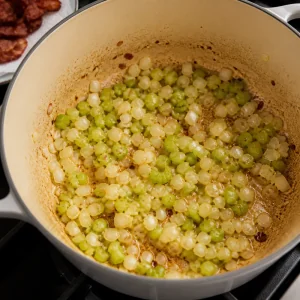 Diced onion and celery softening in bacon fat in a Dutch oven