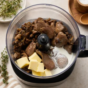 Cooked liver and mushroom mixture in a food processor with butter and cream