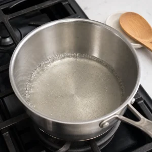 Sugar and water heating in a saucepan as the syrup begins to bubble