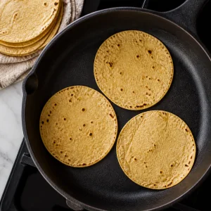 Corn tortillas warming in a dry skillet