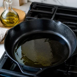 Olive oil heating in a cast iron skillet