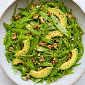 Snow peas tossed with walnut dressing and avocado