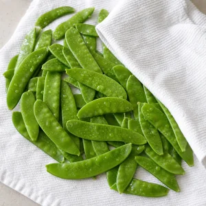 Wet snow peas drying on a clean towel