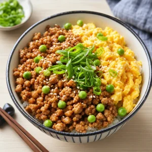 Finished soboro donburi garnished with green onions peas and sesame seeds