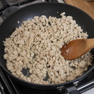 Ground chicken cooking in a skillet and broken into fine crumbles