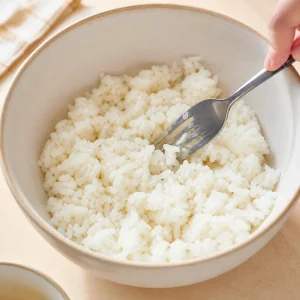 Riso bianco cotto sgranato con una forchetta in una ciotola