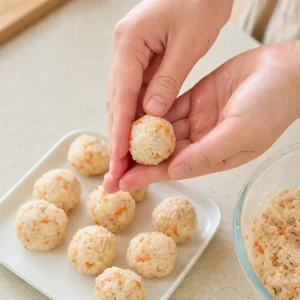 Piccole polpette di pollo e riso modellate a mano su un vassoio