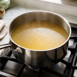 Chicken broth gently simmering in a saucepan for ginger chicken rice soup
