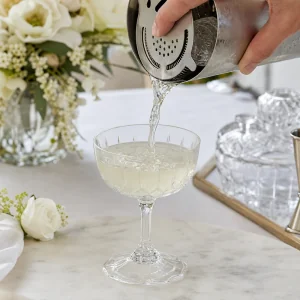 Mistura gelada de gin e sabugueiro coada da coqueteleira para a taca coupe preparada