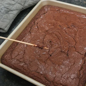 Patyczek sprawdza upieczone brownie z wilgotnymi okruszkami.
